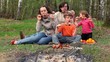 Father, mother and kids, sit on grass and eats kebab Father, mother and kids, sit on grass and eats kebab
