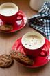 Coffee in red cups with chocolate chip cookies on a wooden board