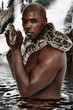 Attractive Fit Black Man with Boa Constrictor Standing in Lake