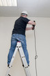 man on a ladder drills drill