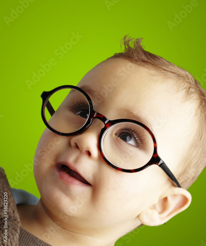 portrait of sweet kid wearing round glasses over green backgroun