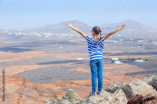 Photo: girl standing on cliff's edge, looking to a sky girl standing on cliff's edge, looking to a sky