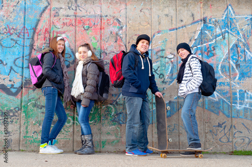 Photo: Happy teenage friends with school bags and skateboards Happy teenage friends with school bags and skateboards