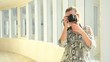 Young beautiful teen taking pictures with camera in the hall
