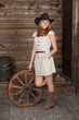 CowGirl with a ancient cart wheel standing in old depot
