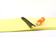 Orange pen on the yellow writing-book Orange pen on the yellow writing-book