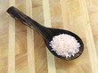 Bolivian Rose salt in a wooden spoon on a wooden table.