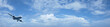 Jet plane in a blue cloudy sky. Panoramic composition in high re