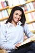 smiling female student with book in hands in a bookstore - model