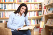 Photo: smiling female student with book in hands sitting in a chair in smiling female student with book in hands sitting in a chair in