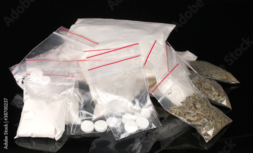 Photo: Cocaine and marihuana in packages on black background Cocaine and marihuana in packages on black background