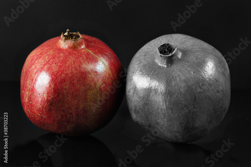 Photo: Two ripe pomegranates on black background Two ripe pomegranates on black background
