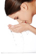 Young female washing her face with clear water