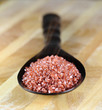 Red Hawaiian sea salt in a wooden spoon on a wooden table.