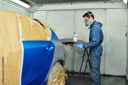 Photo: Worker painting a blue car. Worker painting a blue car.