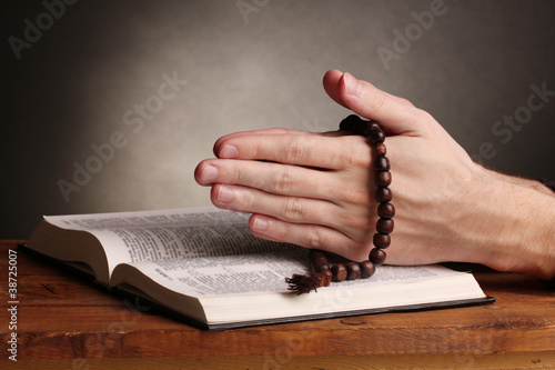 Photo: Hands holding wooden rosary over open russian holy bible Hands holding wooden rosary over open russian holy bible