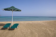 Sunny beach with umbrella and beach chairs