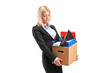 A fired businesswoman in a suit carrying a box of personal items