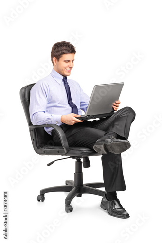 Photo: Young smiling businessman sitting in office chair and working on Young smiling businessman sitting in office chair and working on