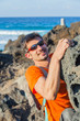 Young man in glasses with backpack climbing