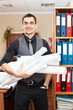 Handsome male business executive standing with rolled blueprints