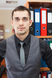 Photo: Handsome male business executive sitting behind a bookstand Handsome male business executive sitting behind a bookstand