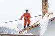 Man cleaning snow off the roof