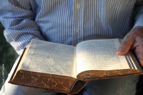 Photo: man reading 1904 German Bible in sunlight man reading 1904 German Bible in sunlight