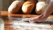 Baker hand throwing flour on the table and kneading dough