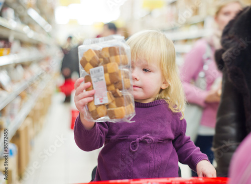 Photo: Mother and daughter in bakery section of supermarket. Daughter w Mother and daughter in bakery section of supermarket. Daughter w