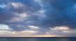 low sun through the clouds, dark ocean