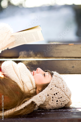 Photo: Woman reading book outdoors at winter time Woman reading book outdoors at winter time