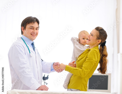 Photo: Mother thanking pediatrician doctor for baby examination Mother thanking pediatrician doctor for baby examination