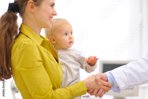 Photo: Closeup on mother with baby thanking pediatrician doctor Closeup on mother with baby thanking pediatrician doctor