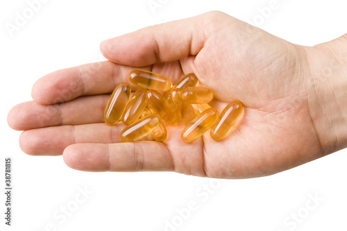 Photo: Male hand holding yellow pills isolated on white Male hand holding yellow pills isolated on white