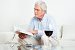 Senior liest ein Buch auf Sofa