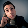 Foto: Funny man talking at the phone against grey background. Funny man talking at the phone against grey background.