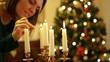 Young woman lighting a candle, christmas tree in background