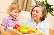 Photo: Grandmother with granddaughter eat fruit at home Grandmother with granddaughter eat fruit at home