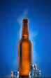 Cold beer bottle with drops, frost and vapour on blue