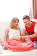 Guy listening baby in pregnant wifes belly using stethoscope