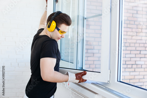 Photo: Man worker mounting window Man worker mounting window