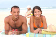 Parents sunbathing as their daughter plays in the sand