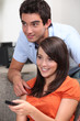 Young couple changing television channel with a remote control