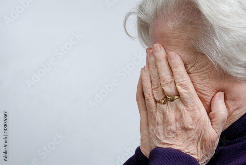 Photo: A crying elderly woman covering her face A crying elderly woman covering her face