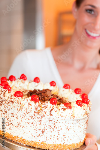 Photo: Bäckerin oder Konditorin mit einer Torte Bäckerin oder Konditorin mit einer Torte
