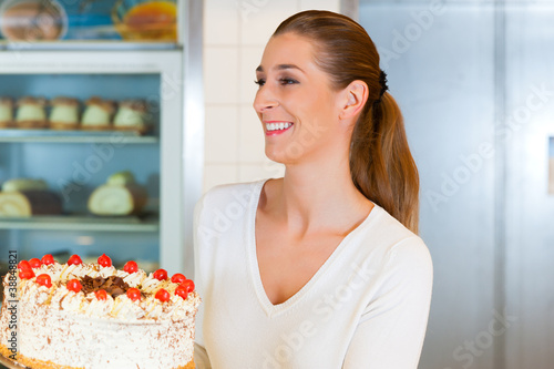 Photo: Female baker or pastry chef with torte Female baker or pastry chef with torte