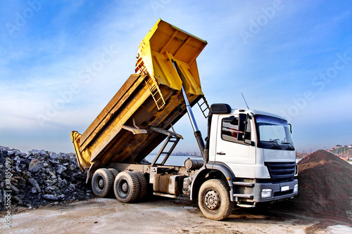 Foto: Dump truck is dumping gravel on an excavation site Dump truck is dumping gravel on an excavation site