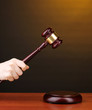 Judge's gavel in hand on brown background