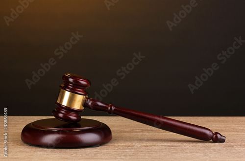 Photo: Judge's gavel on wooden table on brown background Judge's gavel on wooden table on brown background